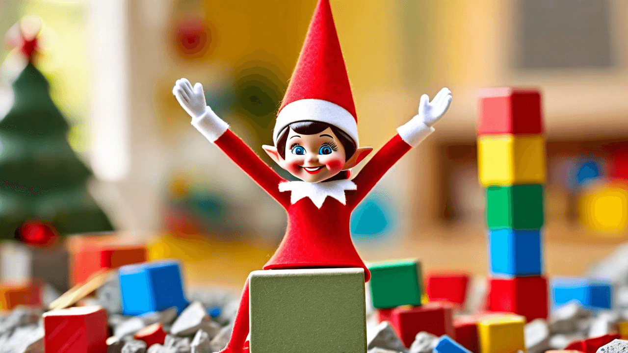 A small elf doll sits triumphantly on top of a pile of colorful scattered building blocks with a tiny paper flag reading 'I WIN!' stuck on its head, surrounded by more blocks in a playful 'blast radius.'